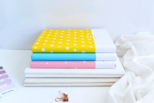A neat stack of colorful notebooks with patterned covers on a white surface showcasing modern design.