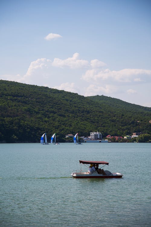 People Riding Pedal Boat on Lake Near Mountain