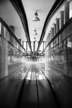 A black and white image capturing a contemporary hallway with sleek reflections and lighting.
