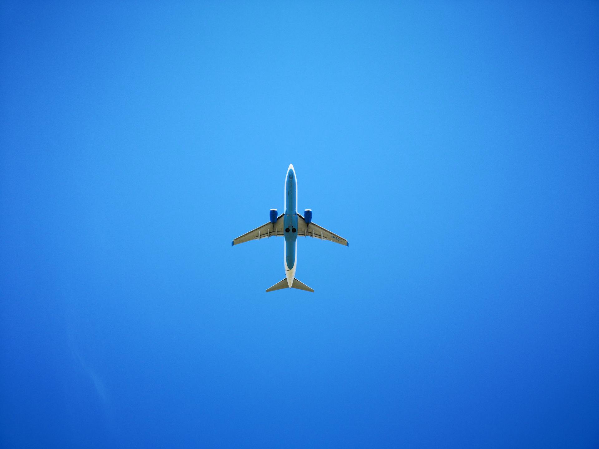 An airplane soaring against a vibrant blue sky, captured from below, representing air travel and freedom.