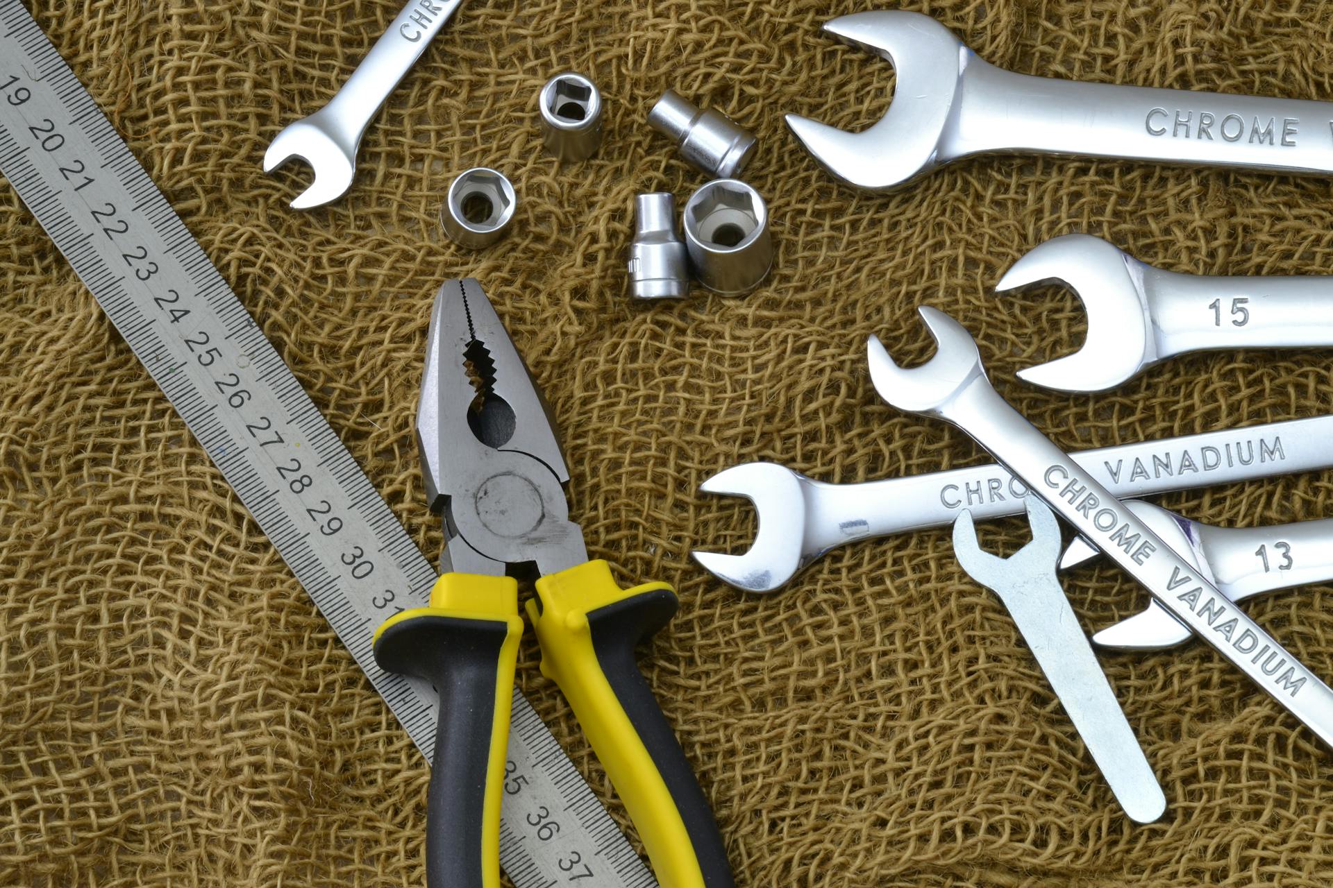 A variety of chrome vanadium tools including pliers and wrenches on burlap.