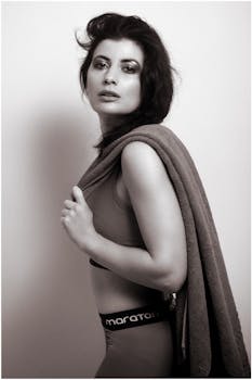 Black and white portrait of a woman posing with a towel in active wear.