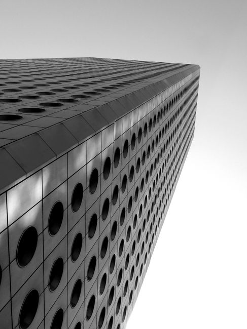 Low angle black and white of creative skyscraper with round shaped windows located in Hong Kong on sunny day