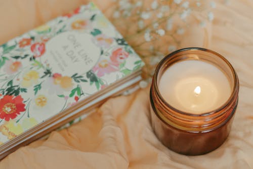 Free Book Beside Candle in Brown Glass Stock Photo