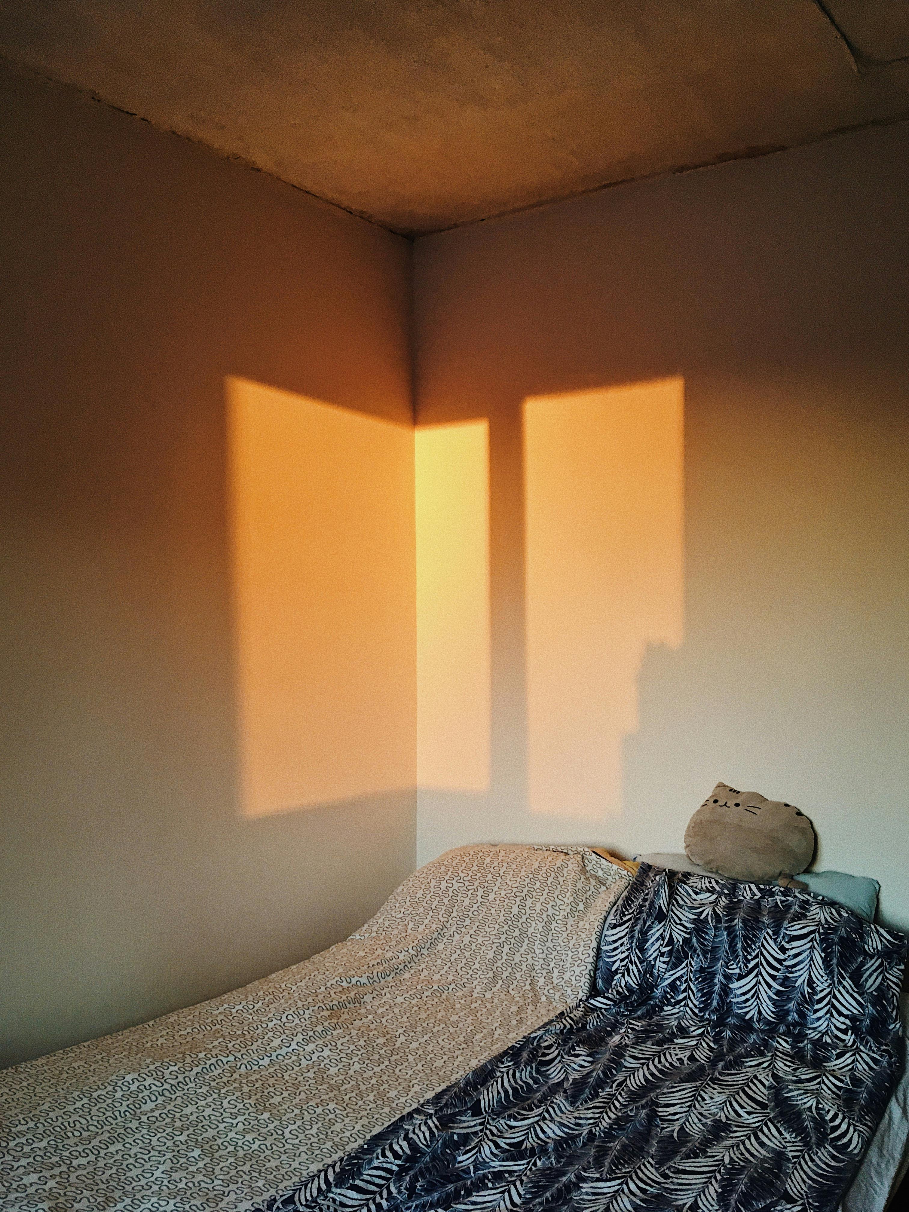 Warm light casts window shadows in a minimalist bedroom, creating a cozy ambiance.