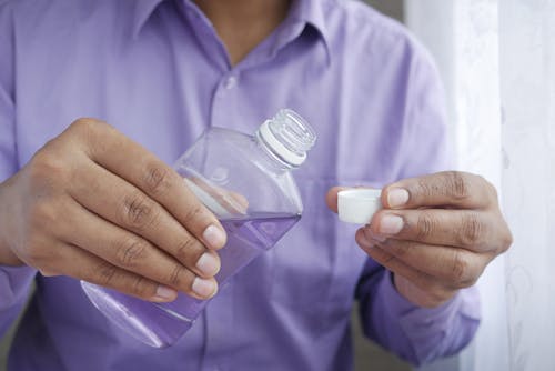 Person Pouring Purple Liquid on Bottle Cap