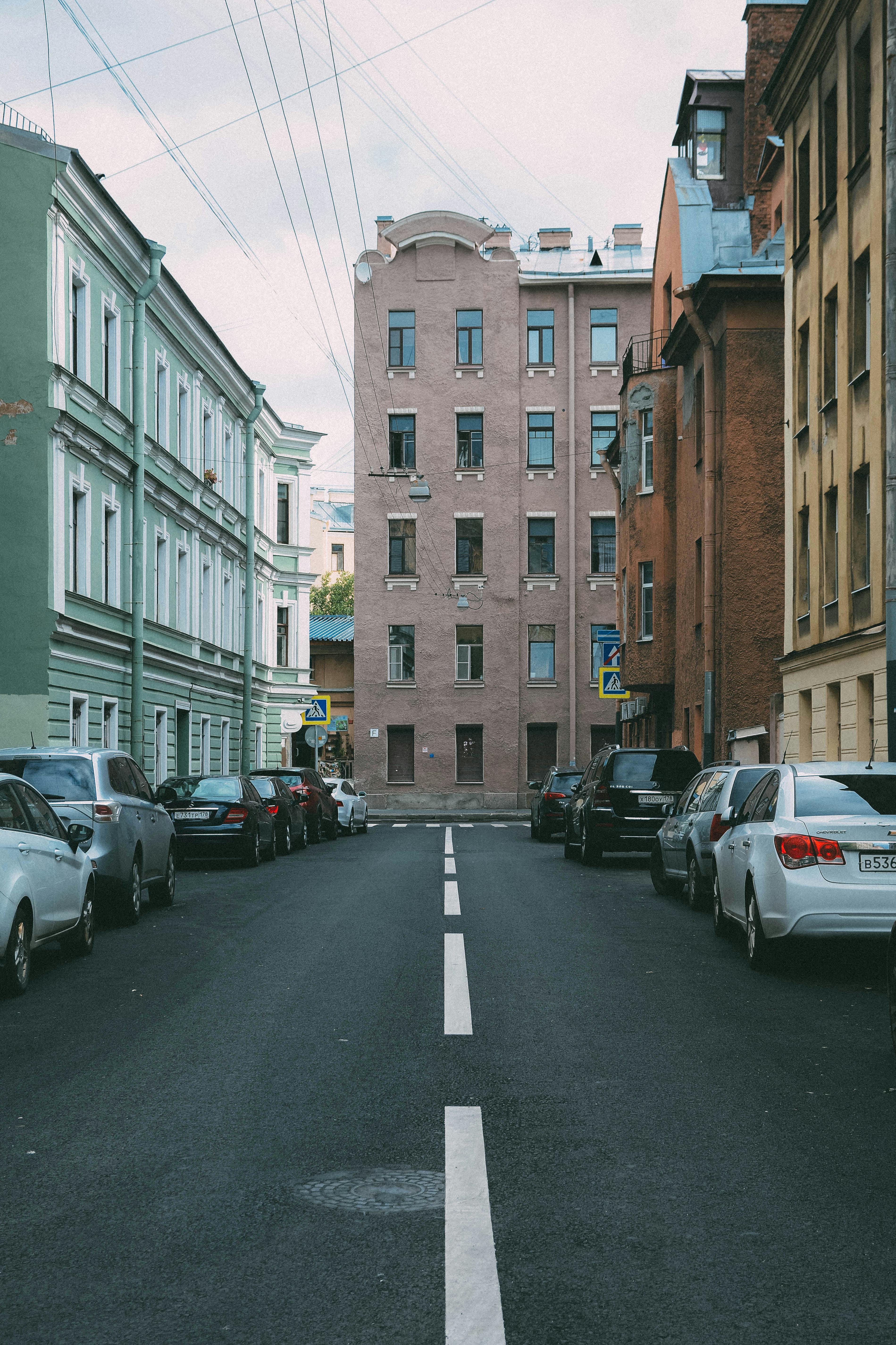 A quiet urban street lined with classic European-style buildings and parked cars.