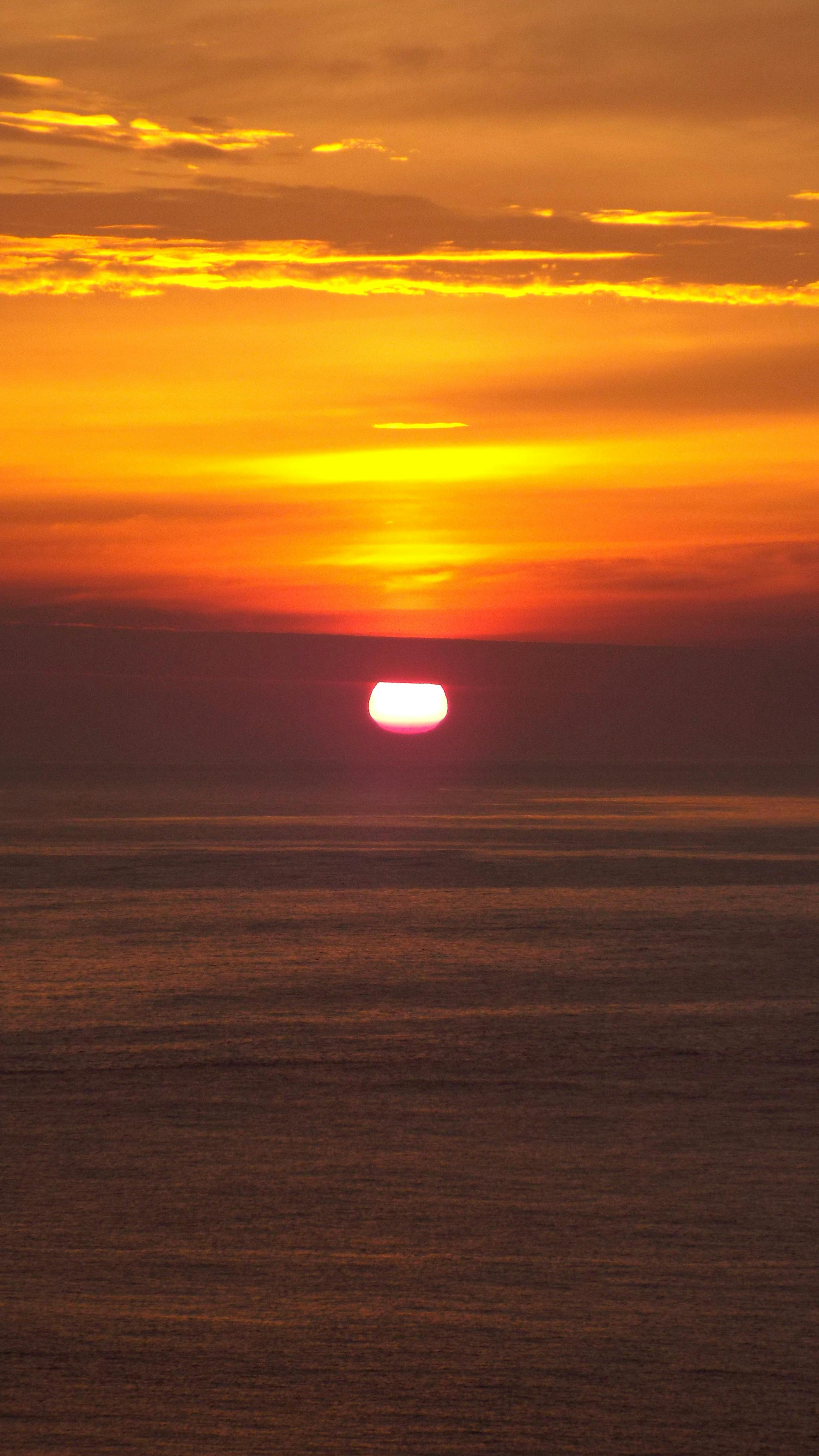 Captivating sunset over the ocean with orange hues and serene water reflections.