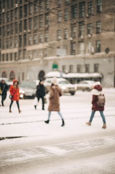 Blurred pedestrians crossing a snowy city street during winter. Urban hustle caught in motion.