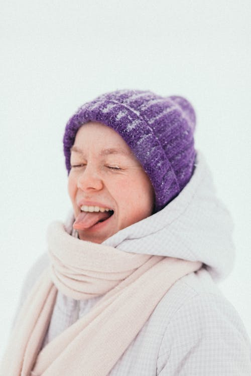 A Smiling Woman in White Sweater Wearing Purple Beanie