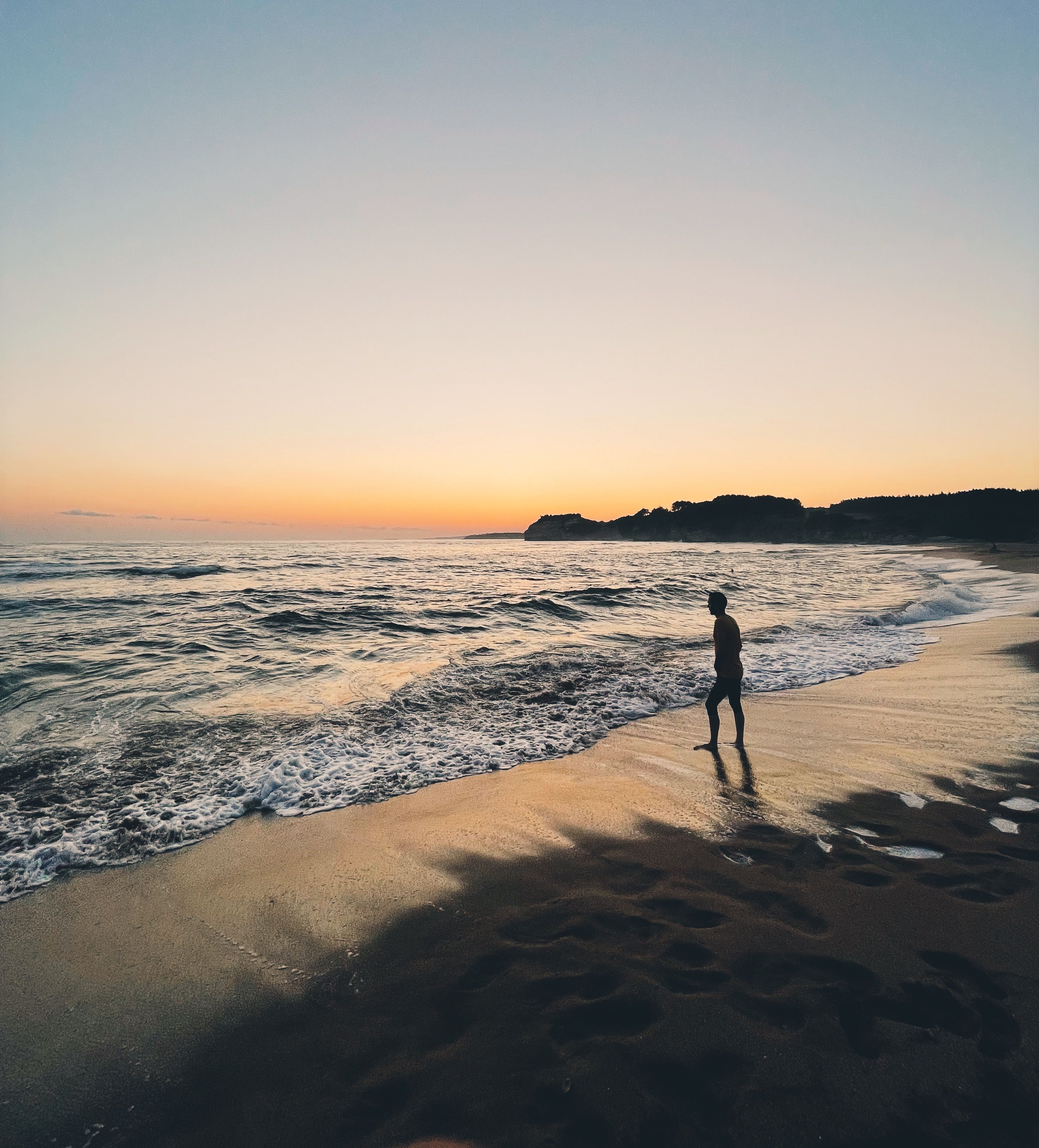 Silhouette of Person Standing on Beach during Sunset · Free Stock Photo