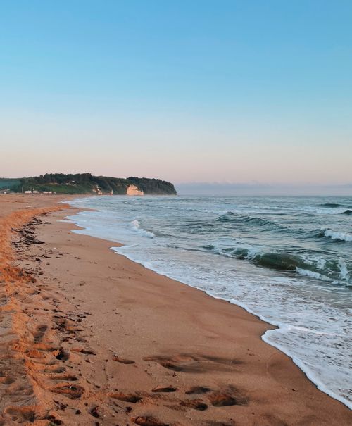 Free Peaceful beach scene in Türkiye at sunrise with gentle waves and clear sky. Stock Photo