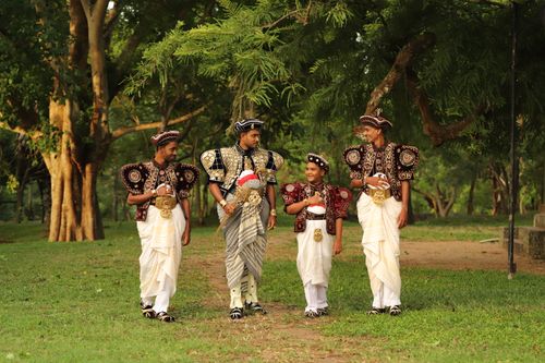 Free Men and boy in traditional Kandyan dress in a lush park setting, Sri Lanka. Stock Photo