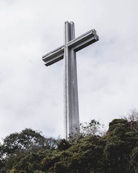 A towering cross monument on Mount Samat in Bataan, against a cloudy sky.