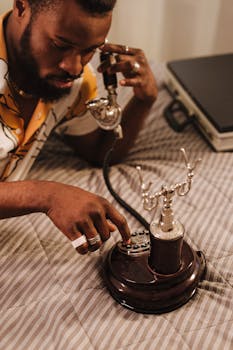 An adult man makes a call using a vintage rotary phone in a cozy indoor setting.