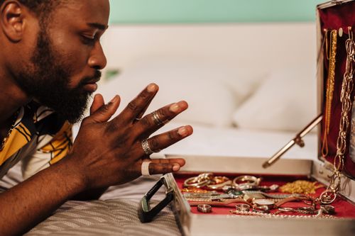 Free Side view of a man contemplating a collection of jewelry displayed in an open box indoors. Stock Photo