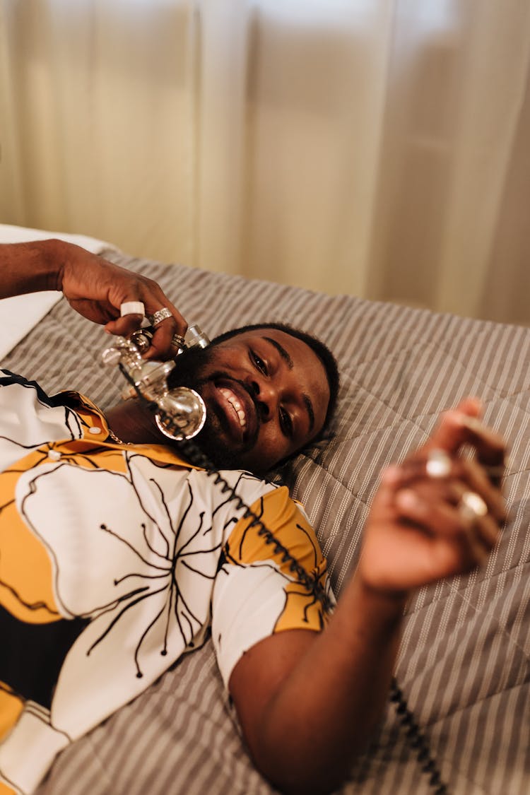 Man Lying On Bed While Talking On The Phone