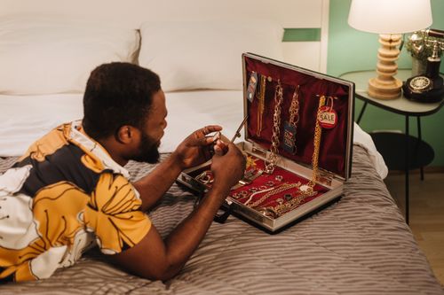 Free Man examining a suitcase filled with luxury jewelry, lying on bed in bedroom. Stock Photo