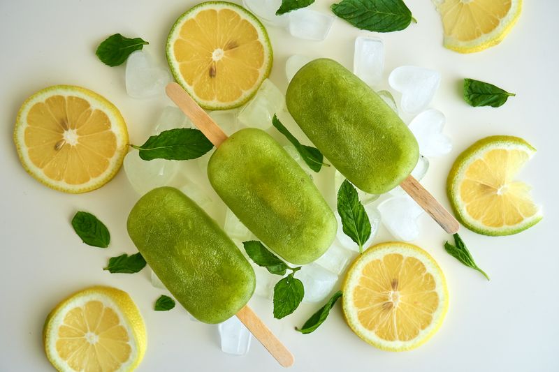 Green ice pops with lemon slices and mint leaves resting on ice
