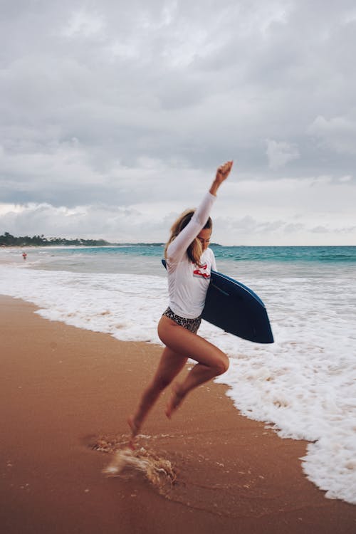 Man Carrying Surfboard in Front Bodies of Water on Brown Sand · Free ...