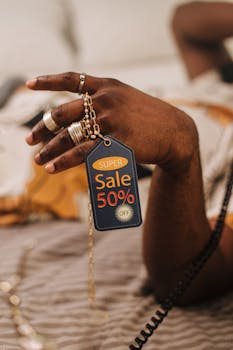 Close-up of a hand holding a sale tag with a 50% discount offer, ideal for promotions.