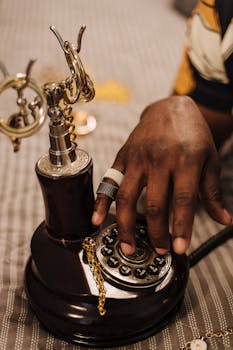 A hand with rings dialing a classic rotary phone, evoking nostalgia.