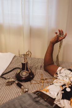Stylish scene with vintage rotary phone, accessories, and lying person on striped bed.