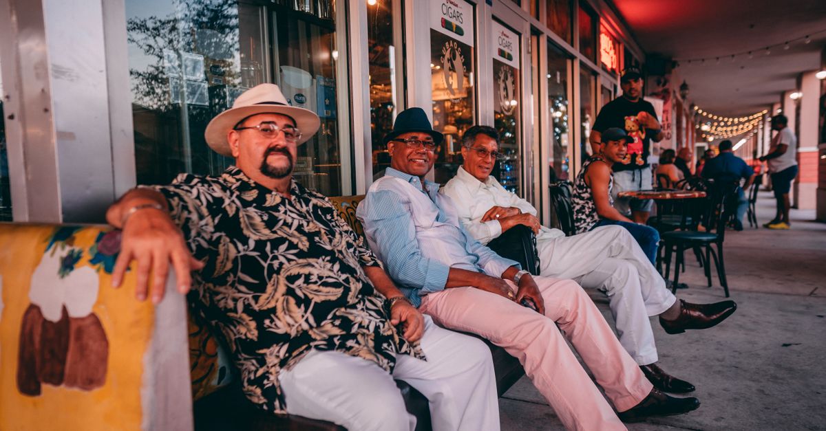 A group of men sit together enjoying a relaxing evening outside a Miami cafe.