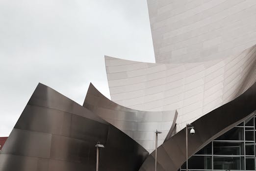 Modern architecture of Walt Disney Concert Hall showcases sleek metallic design under a cloudy sky.