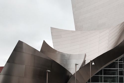 Free Modern architecture of Walt Disney Concert Hall showcases sleek metallic design under a cloudy sky. Stock Photo
