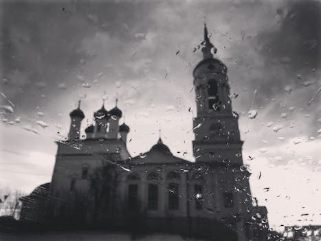 Black and white image of a Russian Orthodox church viewed through raindrops, capturing a moody and dramatic scene.