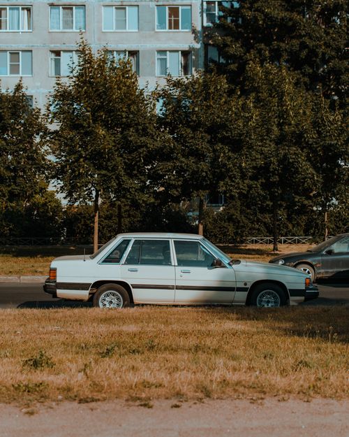 Free White sedan parked in a Saint Petersburg urban setting, surrounded by nature. Stock Photo