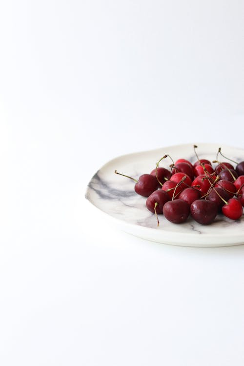 Free Cherries on ceramic plate with tracery Stock Photo