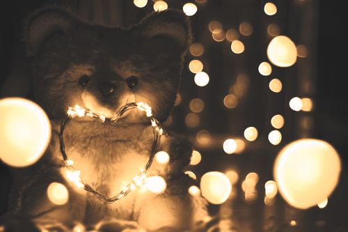 Free A warm, enchanting scene of a teddy bear adorned with heart-shaped string lights, creating a cozy atmosphere. Stock Photo