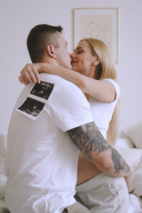 Free Romantic Couple Kissing Each Other while Holding an Ultrasound of Their Baby Stock Photo