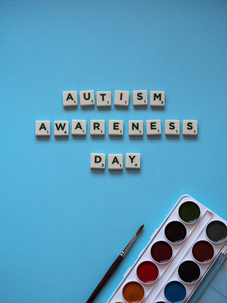 
Letter Tiles And A Set Of Watercolor Paint On A Blue Surface