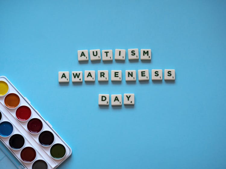 
Letter Tiles And A Watercolor Paint On A Blue Surface