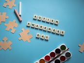 Letter Tiles and a Set of Watercolor Paint on a Blue Surface