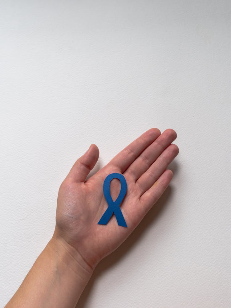 Person With Colon Cancer Awareness Ribbon On Hand