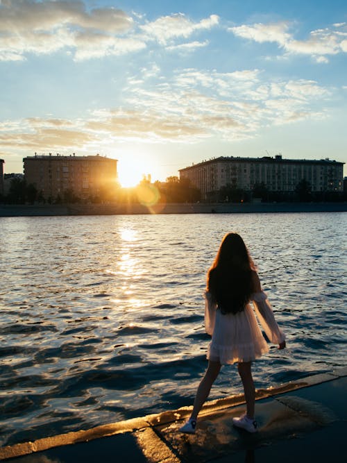 Woman in White Dress Standing on Concrete Dock