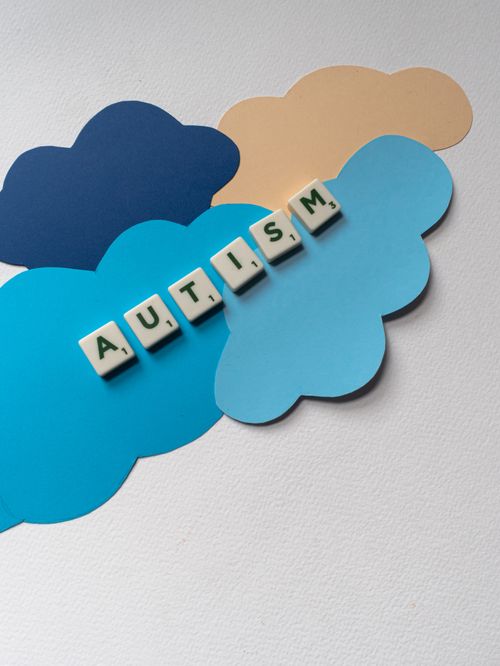 Free Creative depiction of autism awareness using Scrabble tiles and paper clouds in a flat lay style. Stock Photo
