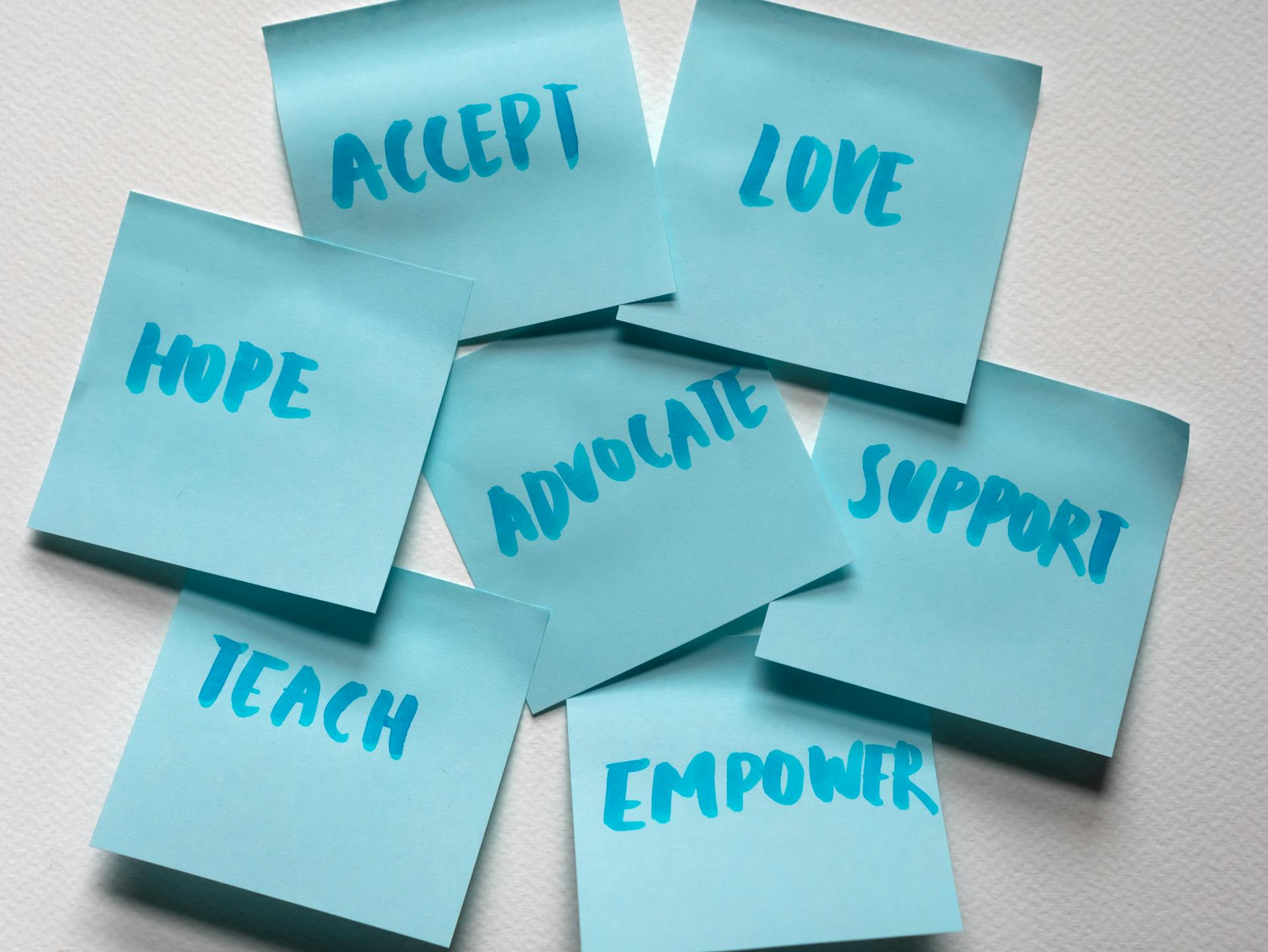 Close-up of blue sticky notes featuring positive words like hope and love.