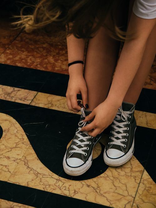 Free Young woman tying shoelaces on a colorful patterned floor in Moscow. Stock Photo