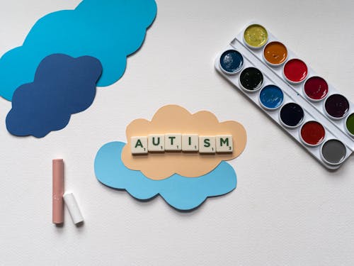 Word Autism Spelled with Scrabble Tiles Placed on Cloud Cutouts