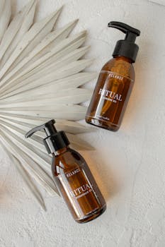 Stylish flat lay of brown pump bottles with a palm leaf on textured surface.
