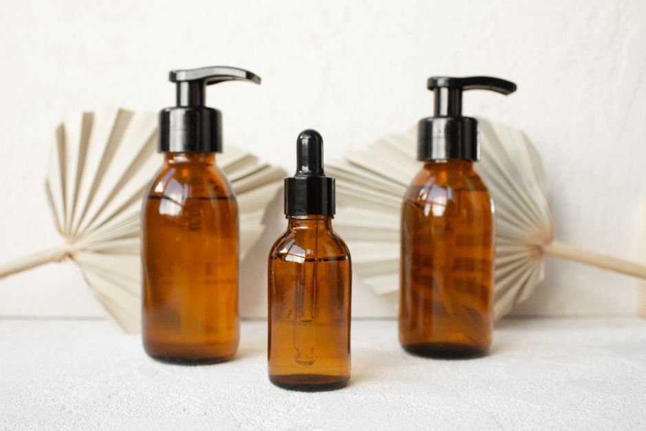 Three amber glass bottles with black caps in a minimalist setup, perfect for skincare or cosmetic products.