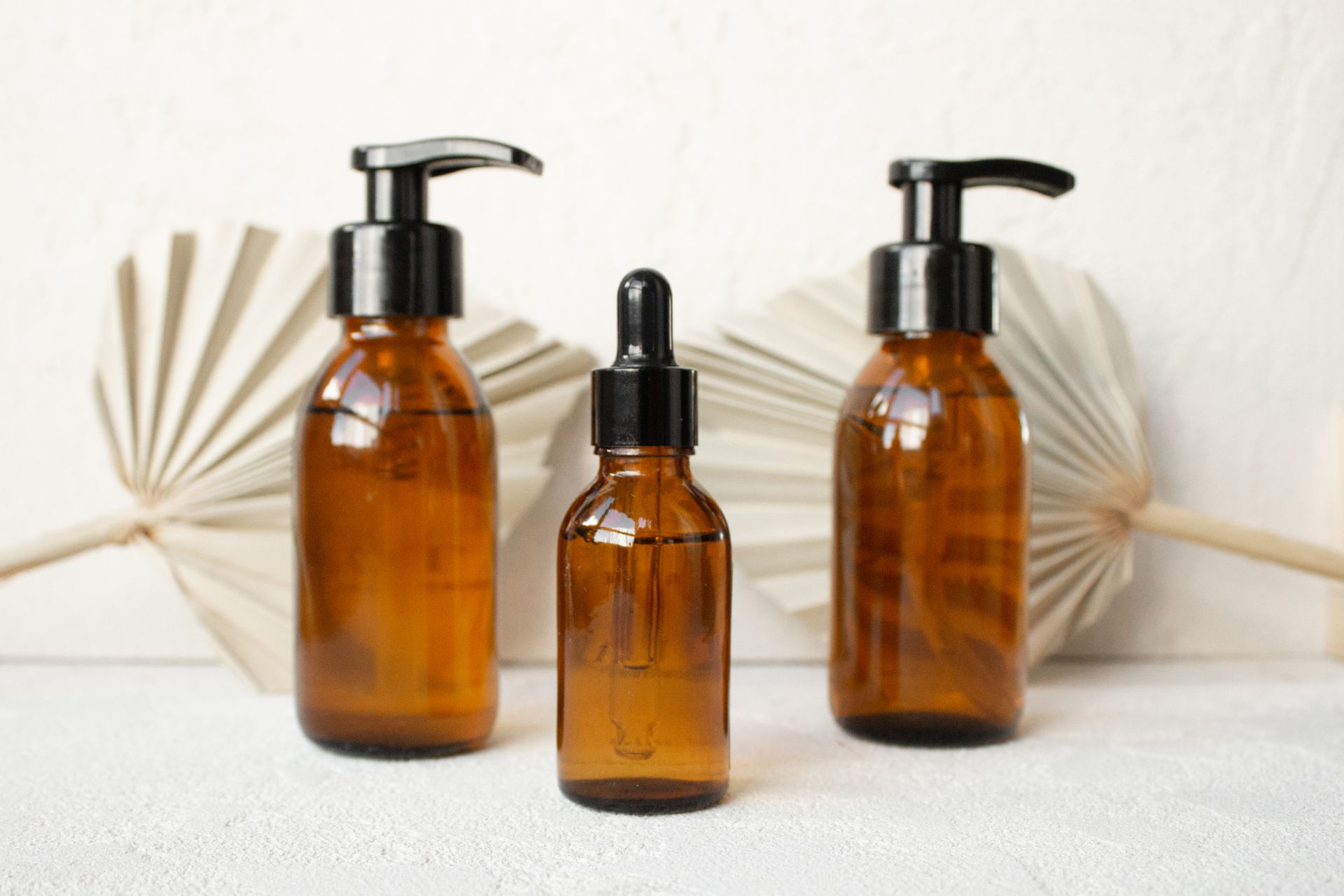 A Brown Squeeze Bottle Between Pump Bottles on White Table