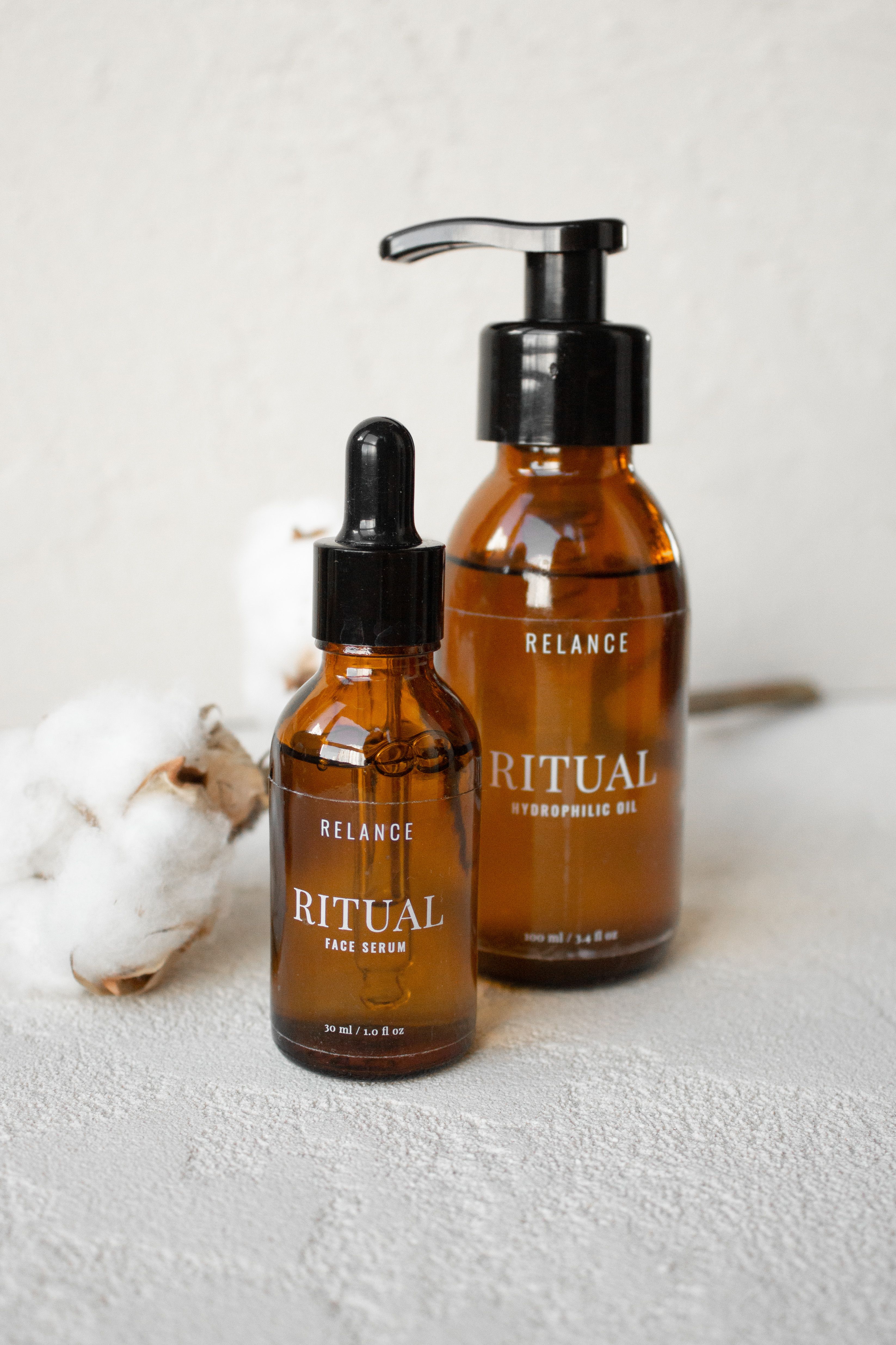 Amber glass skincare bottles arranged on a stone surface with botanical elements