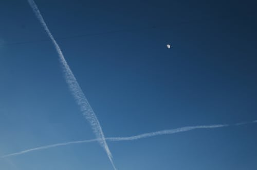 A Moon Over a Line of White Clouds on a Blue Sky