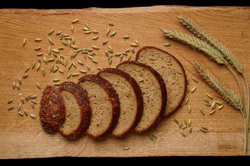 Free A top view of sliced rye bread with whole grains and wheat stalks on a rustic wooden board. Stock Photo